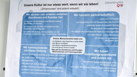 Foto eines Posters, auf dem die Leitsätze des Jobcenters abgebildet sind. Der Titel: Unsere Kultur ist nur etwas wert, wenn wir sie leben! (Bild anzeigen)