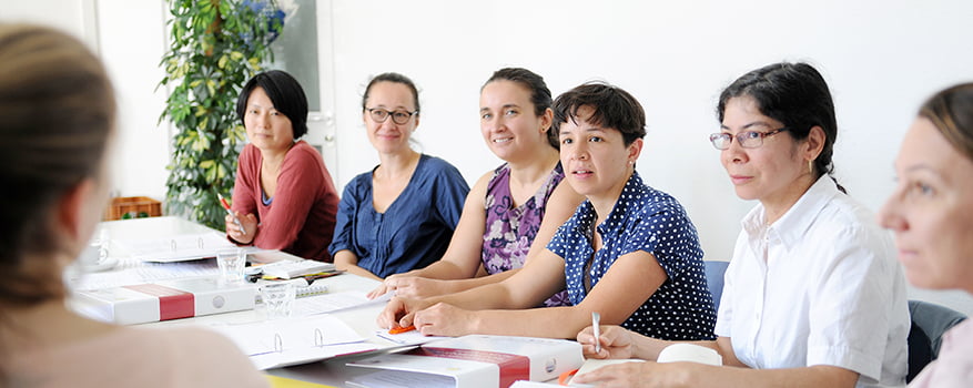 Mehrere Frauen sitzen in einer Arbeitsgruppe am Tisch.