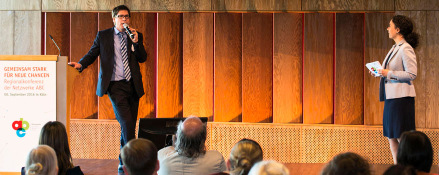 Stefan Frindt im Gespräch mit der Moderatorin Julia Kropf auf einer Bühne vor Publikum.