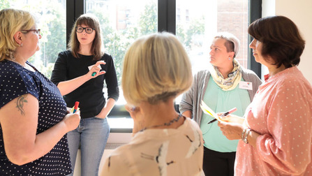 Teilnehmerinnen diskutieren an einer Metaplanwand (Bild anzeigen)