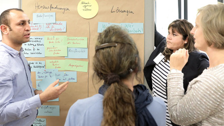 Teilnehmerinnen diskutieren an einer Metaplanwand (ausgwähltes Bild)