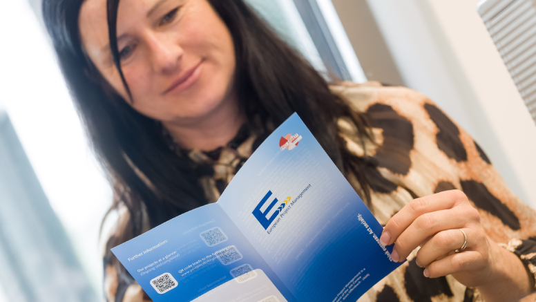 Eine Frau hält den Flyer des European Project Managements in der Hand.