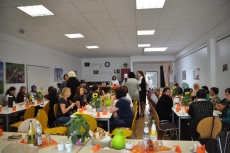 Ein Raum mit geschmückten langen Tischreihen und vielen Menschen.