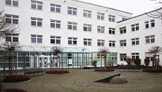 Blick auf ein weißes Gebäude. Davor stehen kahle Platanen auf einem Platz. Öffnet Seite: Jobcenter-Porträt Weiden-Neustadt
