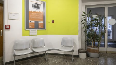 Eingangsbereich des Jobcenters mit drei Stühlen und einer gelben Wand (Bild anzeigen)