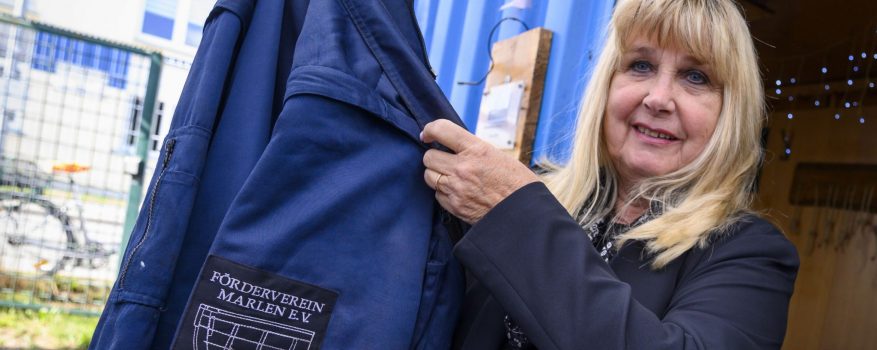 Irmtraud Rakow hält eine blaue Jacke mit dem Aufsticker des "Förderverein Marlen e.V." hoch.