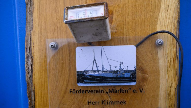 Ein Schild mit der Aufschrift "Förderverein 'Marlen' e.V." mit einem analogen Thermometer darüber.