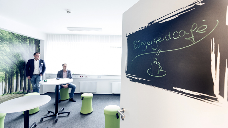 Hereinspaziert: Eine großflächige Fototapete nimmt dem Bürgergeld-Café die Bürostrenge.