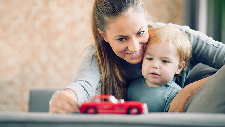 Mutter und Kind spielen mit einem Spielzeugauto.