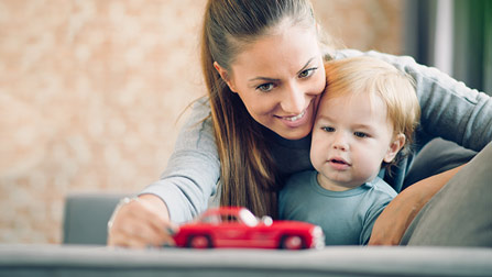 Mutter und Kind spielen mit einem Spielzeugauto.Öffnet Seite: Hinweise zu § 10 Abs. 1 Nr. 3 SGB II