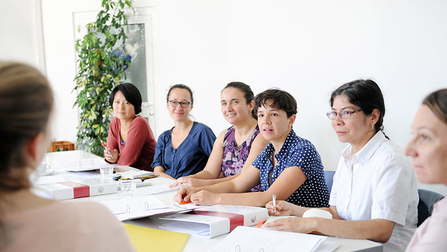 Mehrere Frauen sitzen in einer Arbeitsgruppe am Tisch.Öffnet Seite: Stark unterstützt dank "Stark im Beruf": Mütter mit Migrationshintergrund und Jobcenter profitieren langfristig