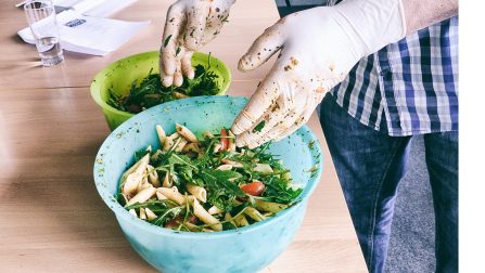 Hände in Hygienehandschuhen bereiten Salat zu.Öffnet Seite: So einzigartig wie möglich