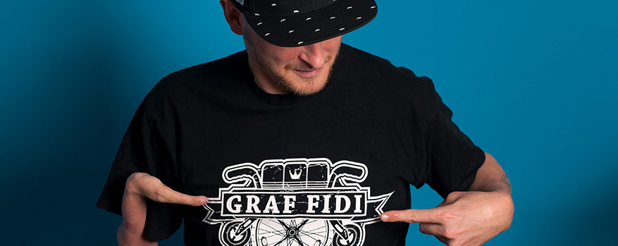 Portrait von Graf Fidi, er trägt ein T-Shirt mit seinem Namen darauf gedruckt.