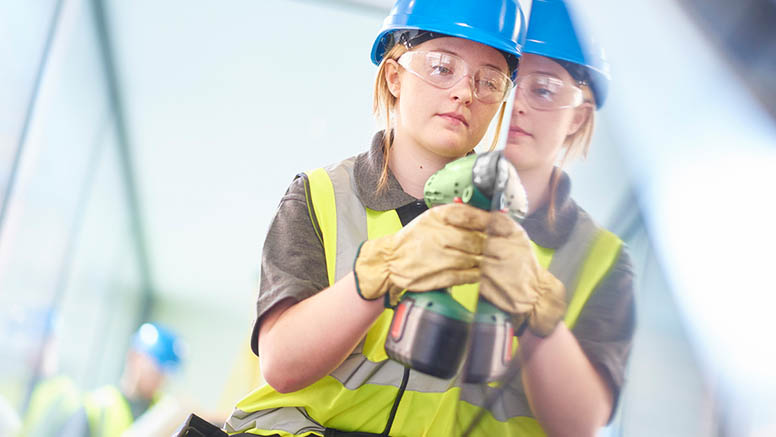 Eine junge Frau mit Helm und Schutzbrille beim Anschrauben einer Glasplatte