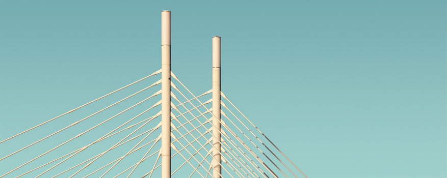 Zwei weiße Brückenpfeiler vor hellblauem Himmel.